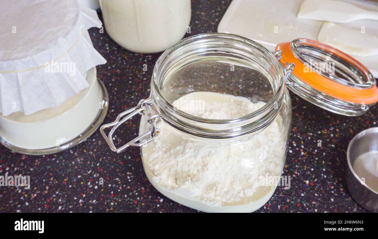 Feeding sourdough starter with water and flour Stock Photo Alamy