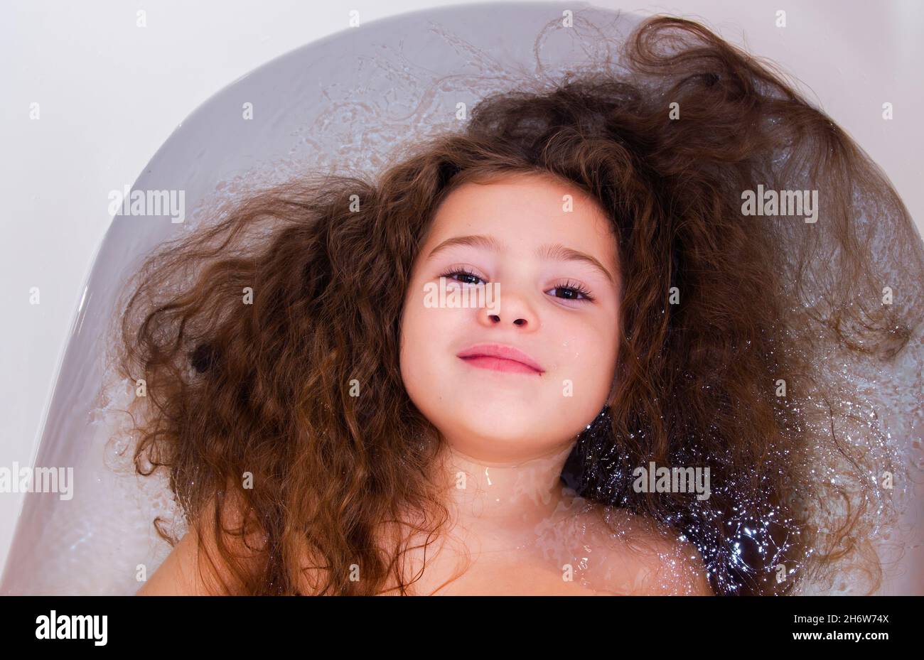 Sweet toddler baby girl in bath. Child girl bathes in a white bathtub. Childhood cleanliness