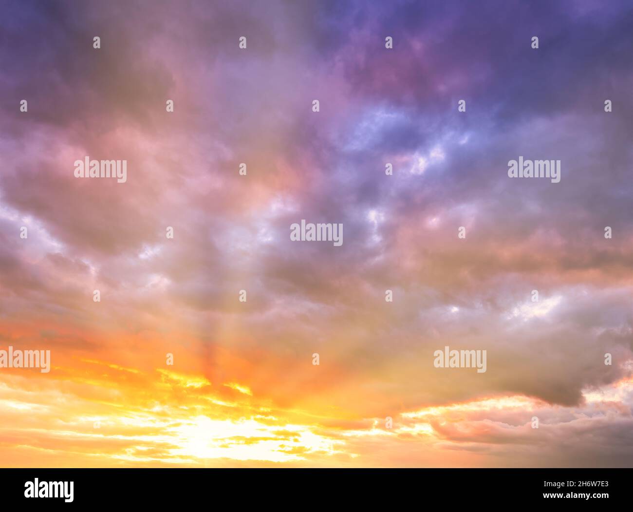 Dramatic cloudy sky at sunset or sunrise. The sun's rays breaking through the clouds. Stock Photo