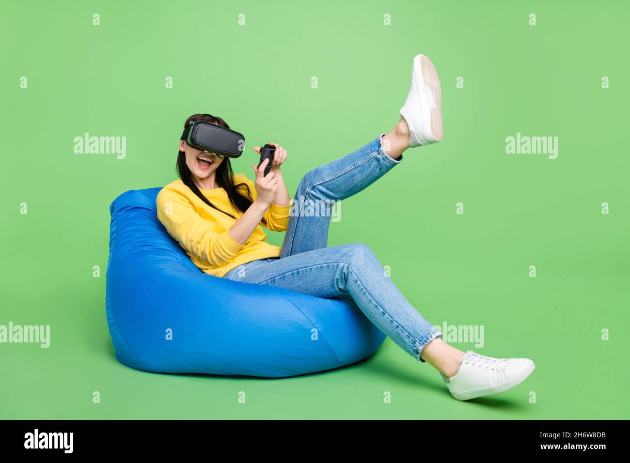 Full length body size photo of woman in beanbag playing video game in virtual reality glasses isolated bright green color background Stock Photo
