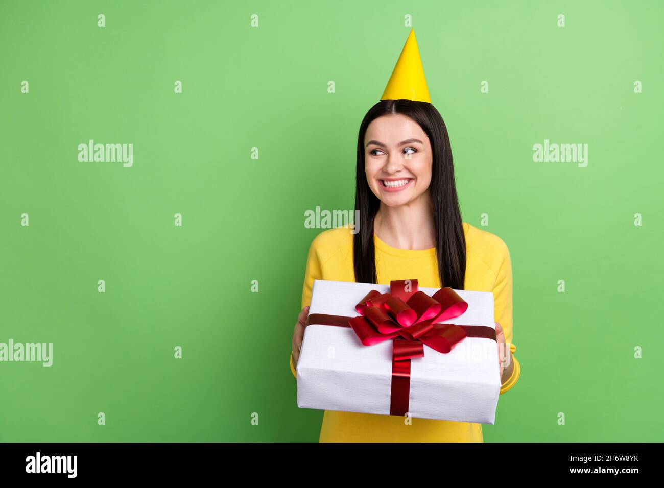 Portrait of attractive curious cheerful girl holding giftbox looking aside copy space isolated over green color background Stock Photo