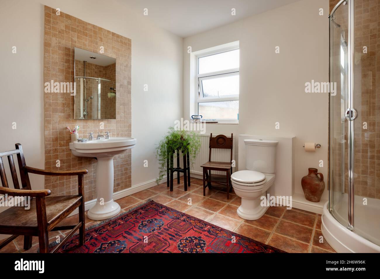 Cambridge, England - October 29 2019: Shower and Bathroom with white painted walls, tiled floor, toilet and sink Stock Photo
