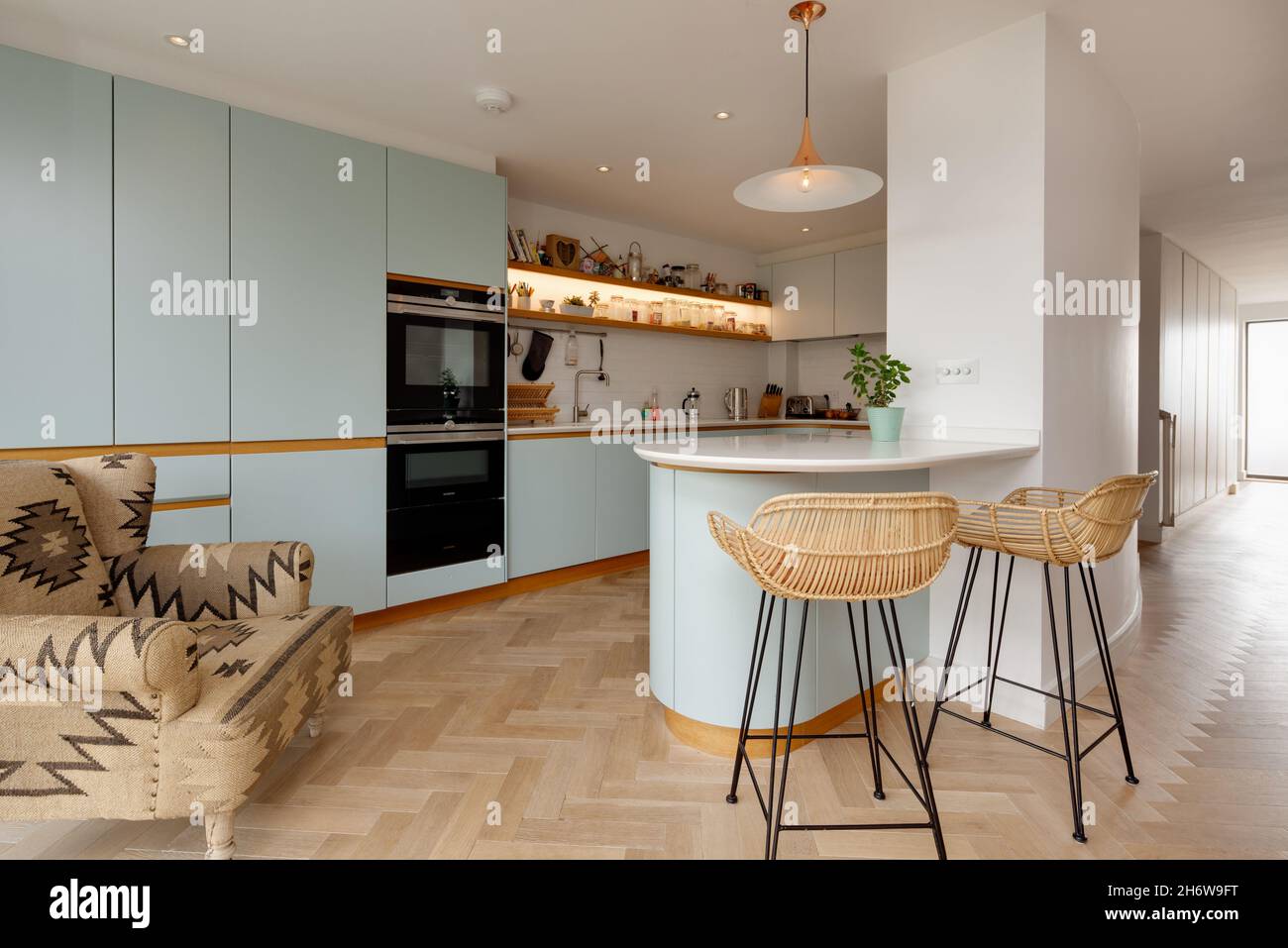 Dry Drayton, England - August 2 2019: Contemporary breakfast bar with complimentary stools within modern house kitchen room, fitted cupboards and buil Stock Photo