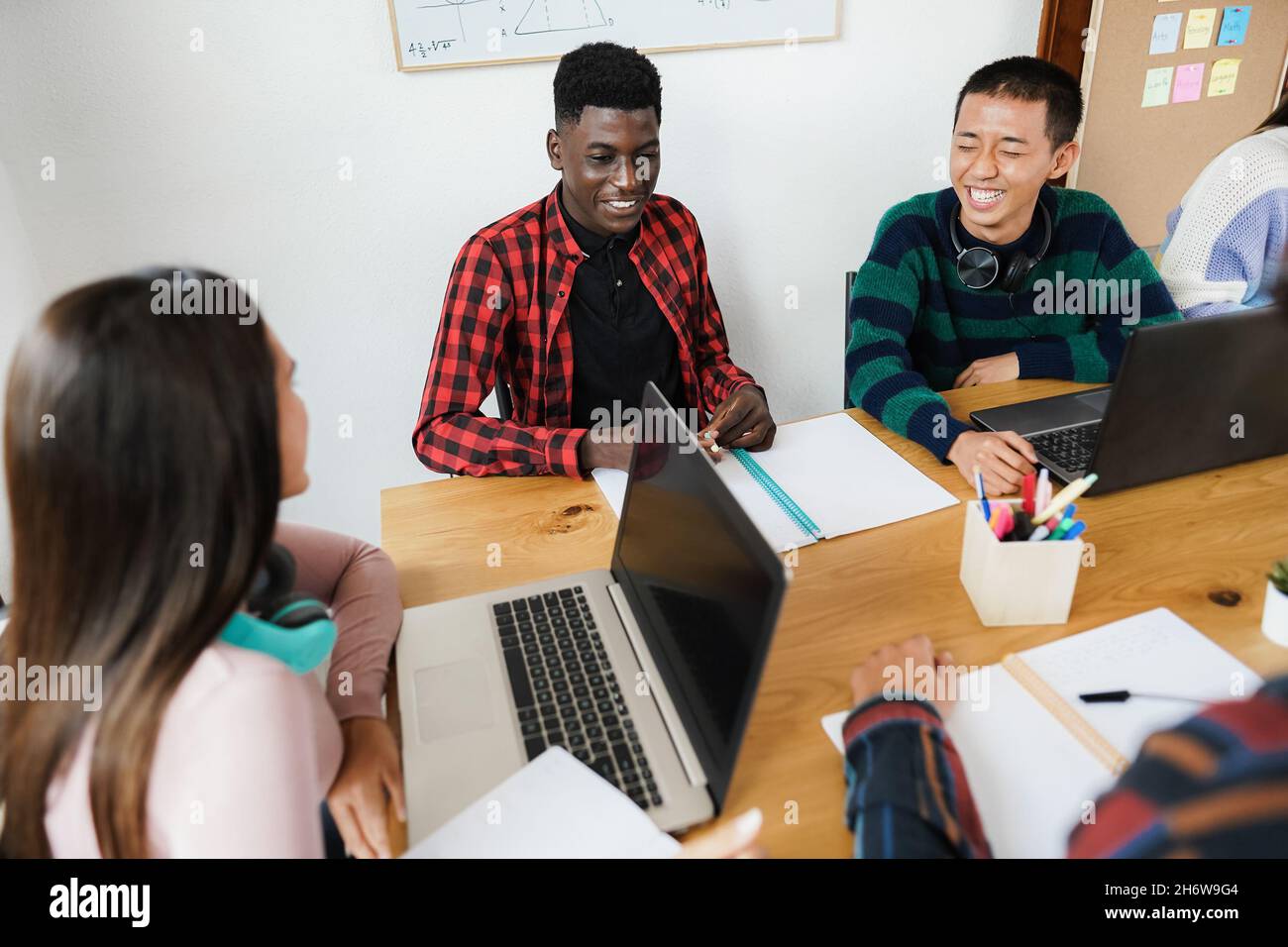 Multiracial students using laptop computers while studying together at school - Focus on african man face Stock Photo
