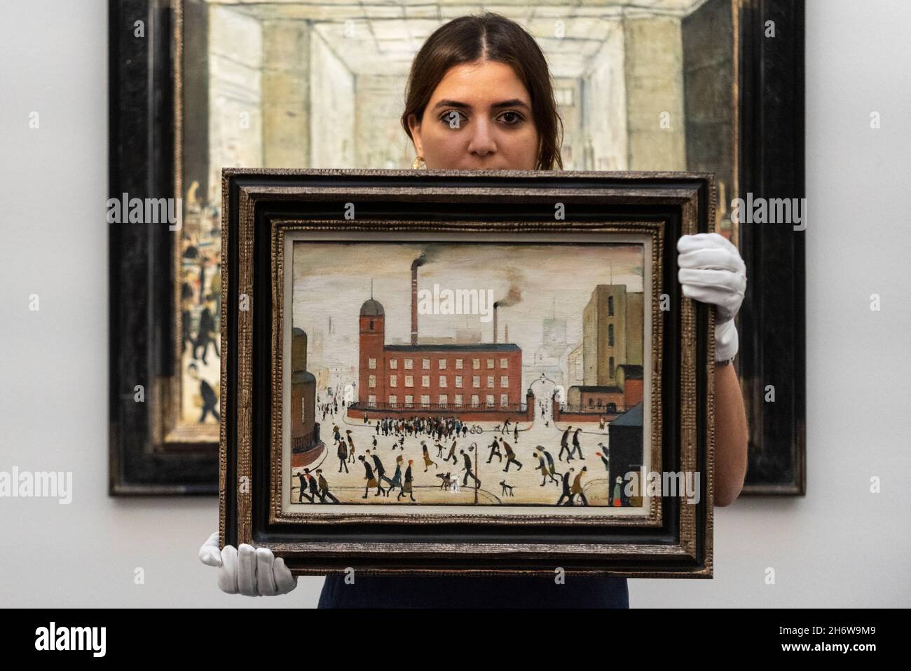 London, UK.  18 November 2021. A technician presents 'Mill Scene', 1959, by Laurence Stephen Lowry (Est.£300,000-500,000) at the preview of the upcoming Modern British and Irish art sale at Sotheby’s New Bond Street.  Credit: Stephen Chung / Alamy Live News Stock Photo