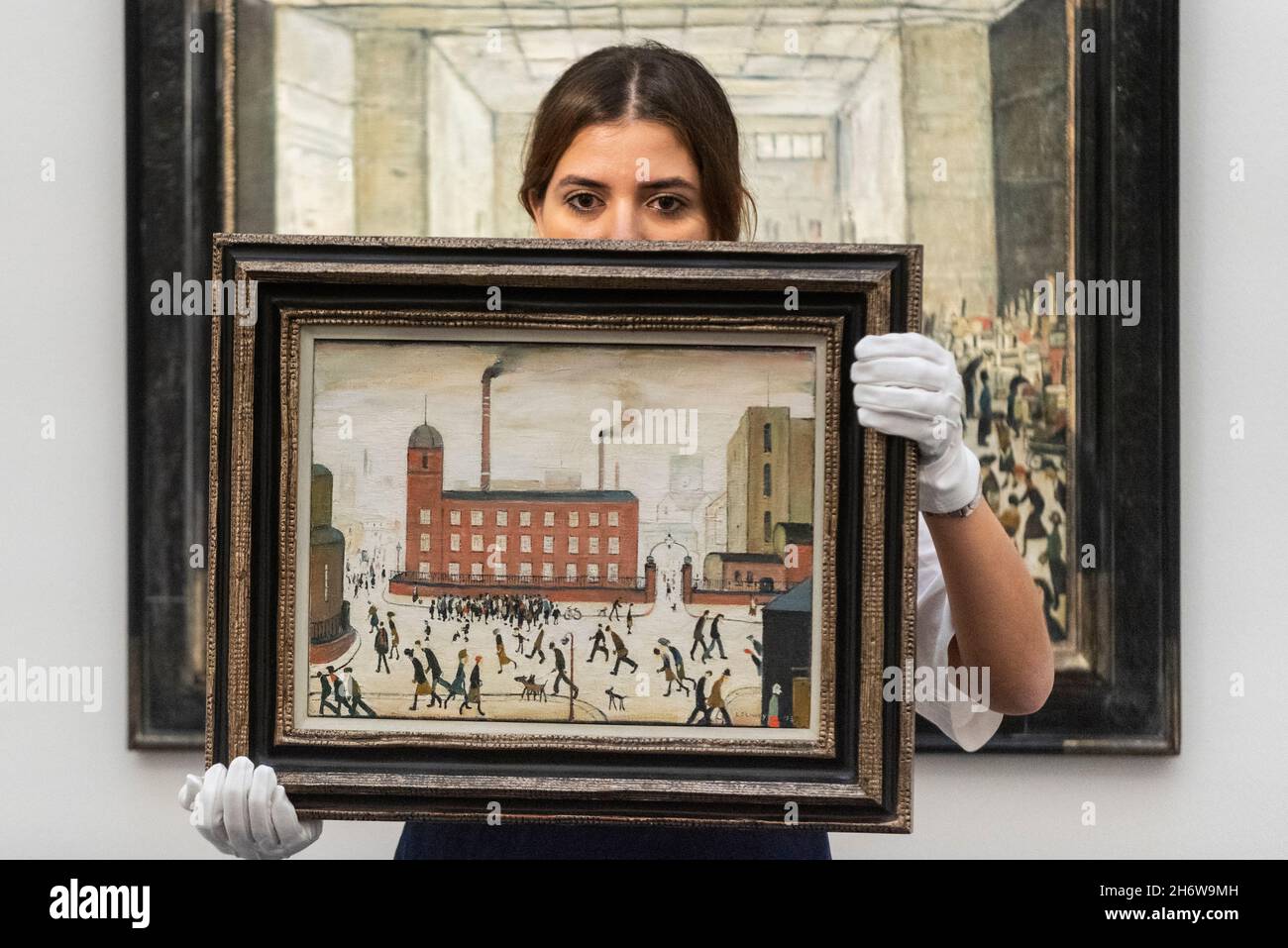 London, UK.  18 November 2021. A technician presents 'Mill Scene', 1959, by Laurence Stephen Lowry (Est.£300,000-500,000) at the preview of the upcoming Modern British and Irish art sale at Sotheby’s New Bond Street.  Credit: Stephen Chung / Alamy Live News Stock Photo