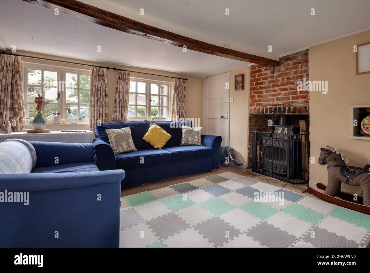Hargrave, Suffolk, England - June 10 2020: Traditional English Country Cottage lounge or living room with cast iron wood burning stove and low ceiling Stock Photo