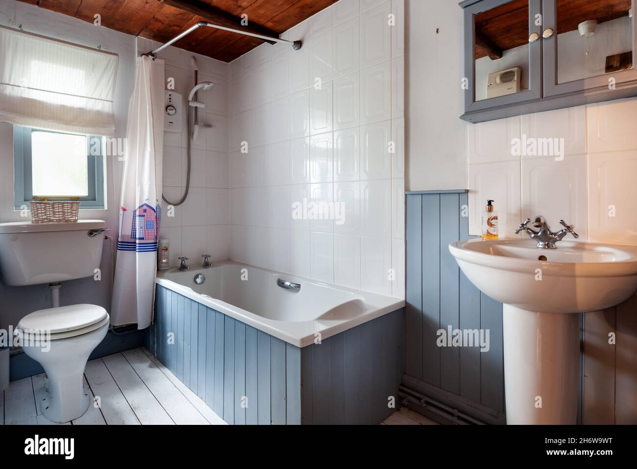 Kedington, Suffolk - November 19 2019: Compact cottage bathroom and wc inside British cottage with tiled and panelled walls, sink , toilet and bath Stock Photo