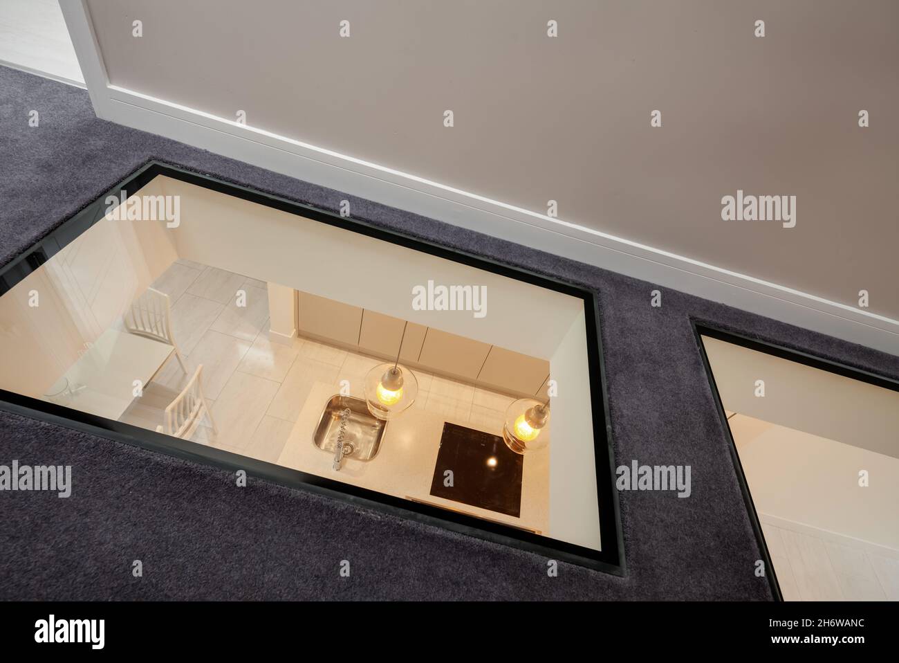 Cambridge, England - August 16 2019: Modern first floor landing area in renovated vacant house with unusual glass floor looking down into kitchen Stock Photo