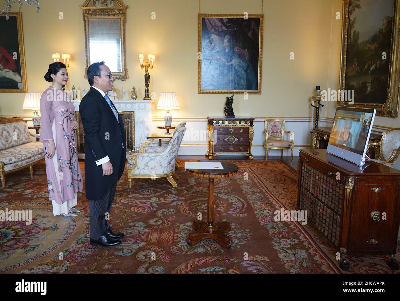 Queen Elizabeth II appears on a screen via videolink from Windsor Castle, where she is in residence, during a virtual audience to receive Nguyen Hoang Long, the Ambassador from the Socialist Republic of Vietnam, and his wife Vu Huong Giang, at Buckingham Palace, London. Picture date: Thursday November 18, 2021. Stock Photo