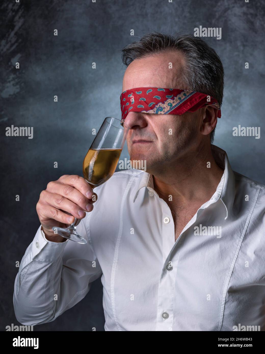 A blindfolded man sniffs a glass of wine to smell its aroma Stock Photo