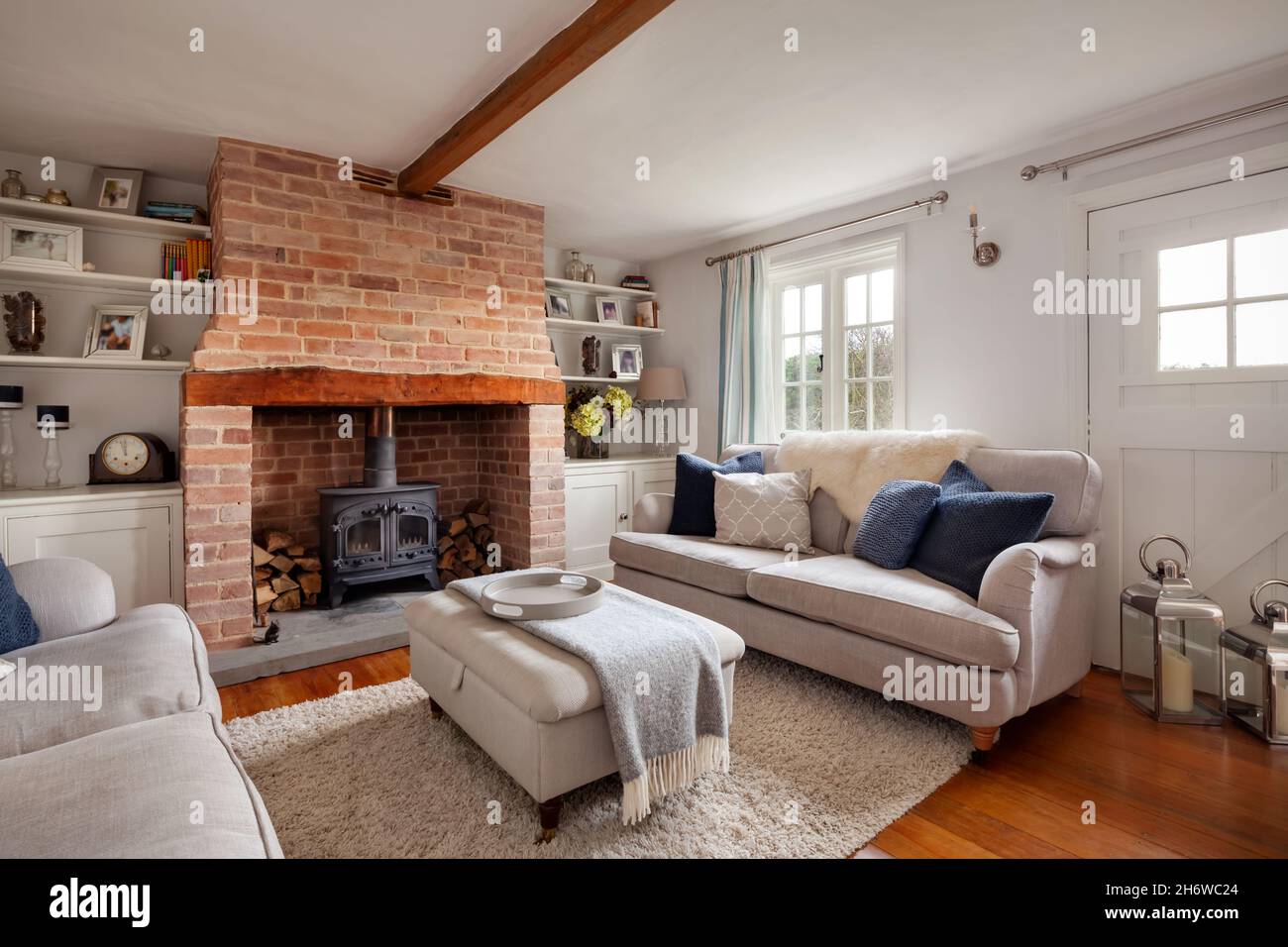Calford Green, Suffolk, England - January 17 2020: Fully furnished cottage living room with log burner and exposed brick inglenook fireplace Stock Photo
