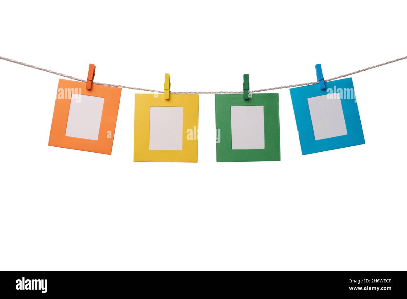 Four multicolored paper photo frames hanging on the rope with wooden clothespins isolated on white background Stock Photo