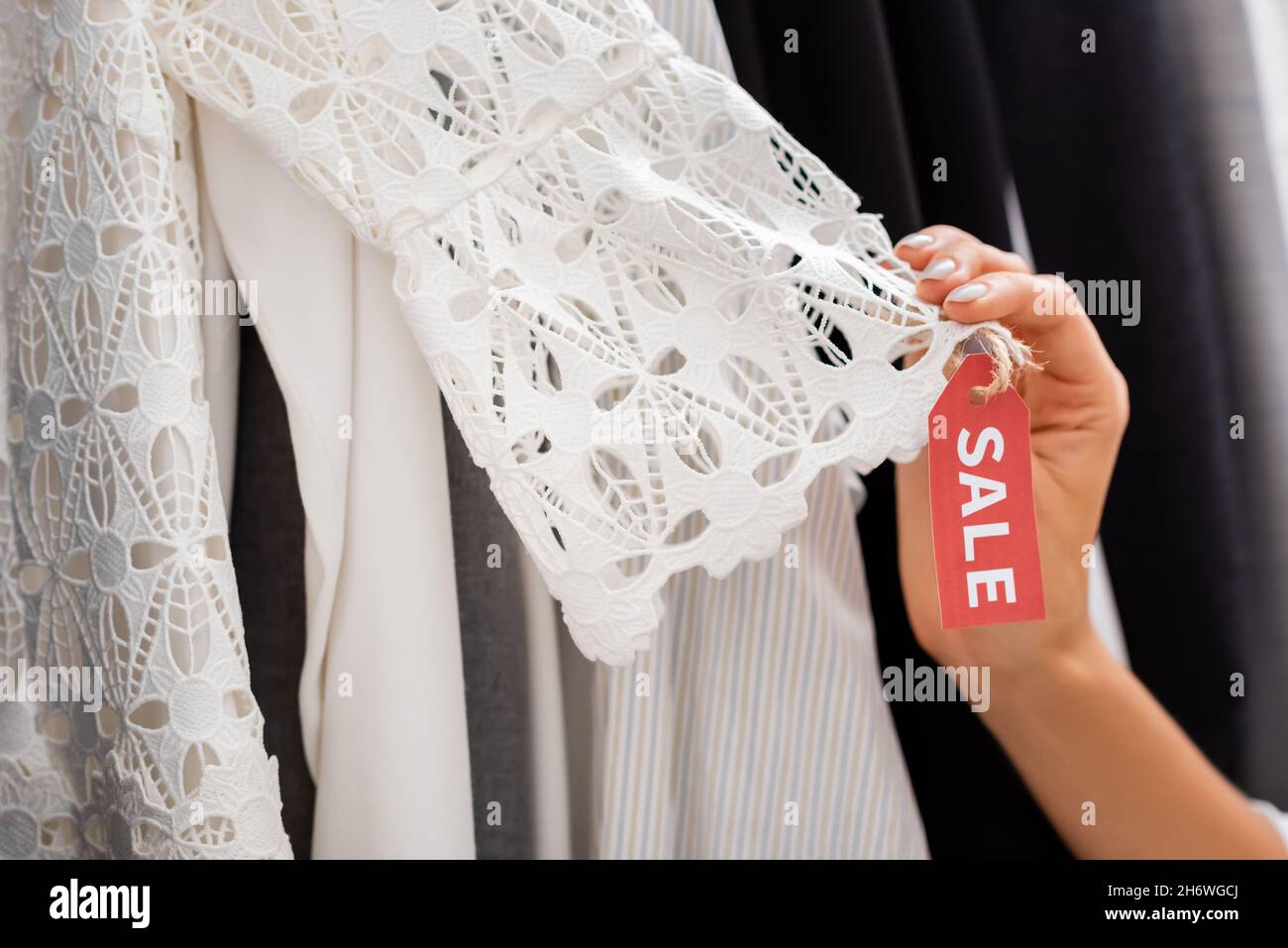 cropped view of customer holding guipure clothing with sale tag Stock Photo