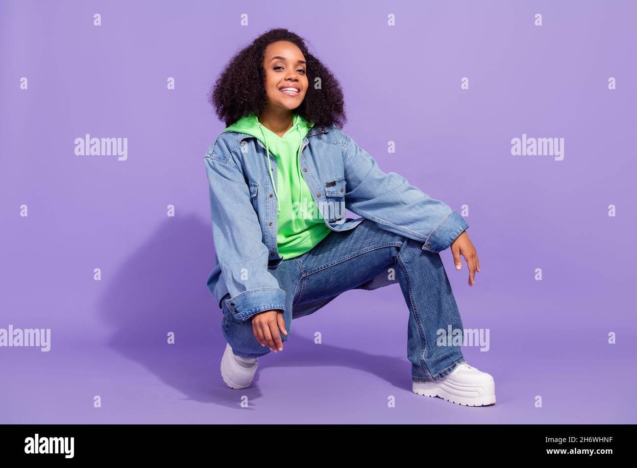 Full length photo of satisfied candid person squat beaming smile look  camera isolated on purple color background Stock Photo - Alamy