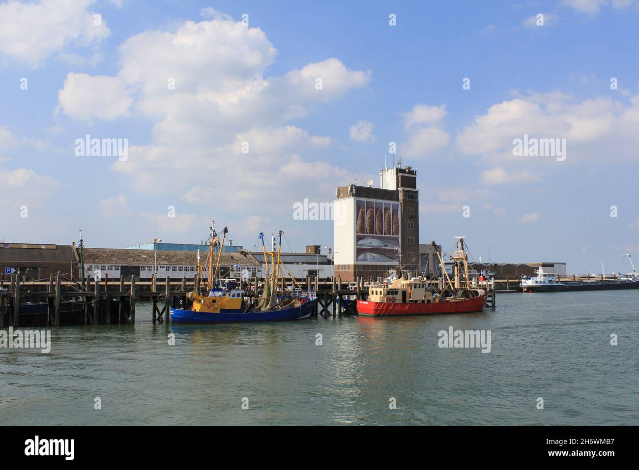 the harbor in fishing port breskens at the dutch coast with two fishing boats and a big artwork 'bread and fish' at a grain silo at the quay in summer Stock Photo