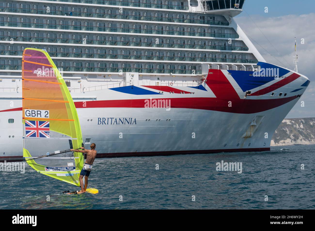 Tom Squires windsurfing past the MV Britannia P&O cruise ship at Weymouth Bay on the 21st July 2020 in Portland, Dorset in the United Kingdom. Stock Photo