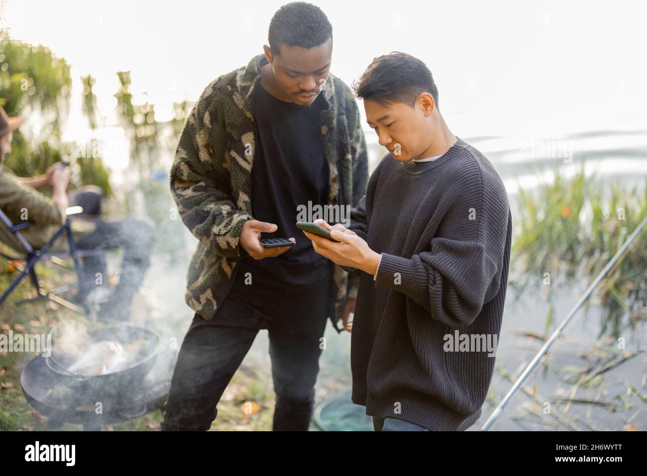 Men using smartphones during resting on pond coast Stock Photo