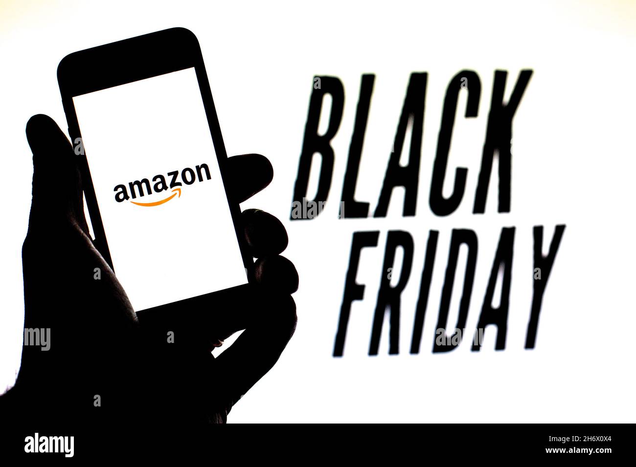 In this photo illustration, a Amazon.com logo is seen on a smartphone screen with 'Black Friday' words in the background. Stock Photo