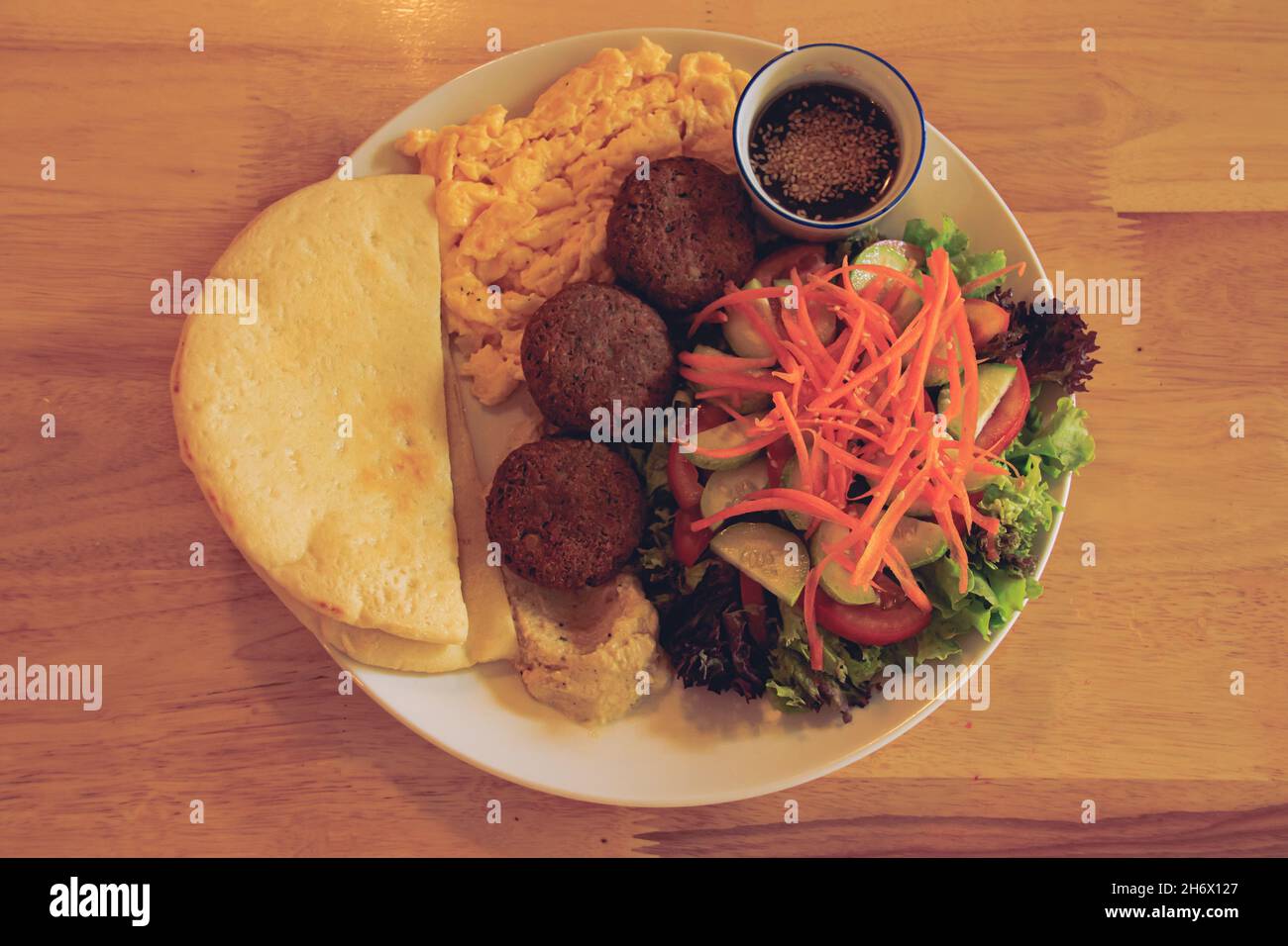 Pita bread, falafel, hummus, salad and scrambled eggs for a healthy