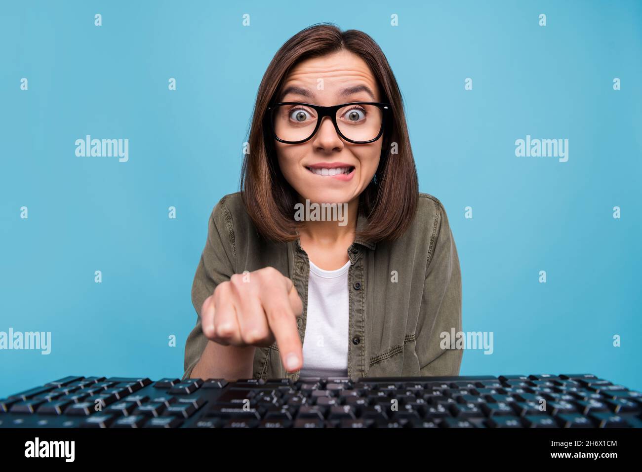 Portrait of anxious computer nerd lady press keyboard button look webcam social media isolated over blue color background Stock Photo