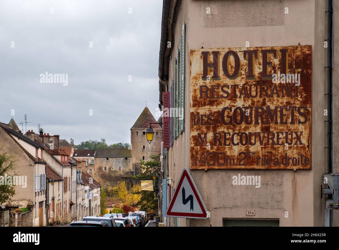 An old weathered hotel sign on Rue de Paris outside the walled town of Semur-en-Auxois Stock Photo