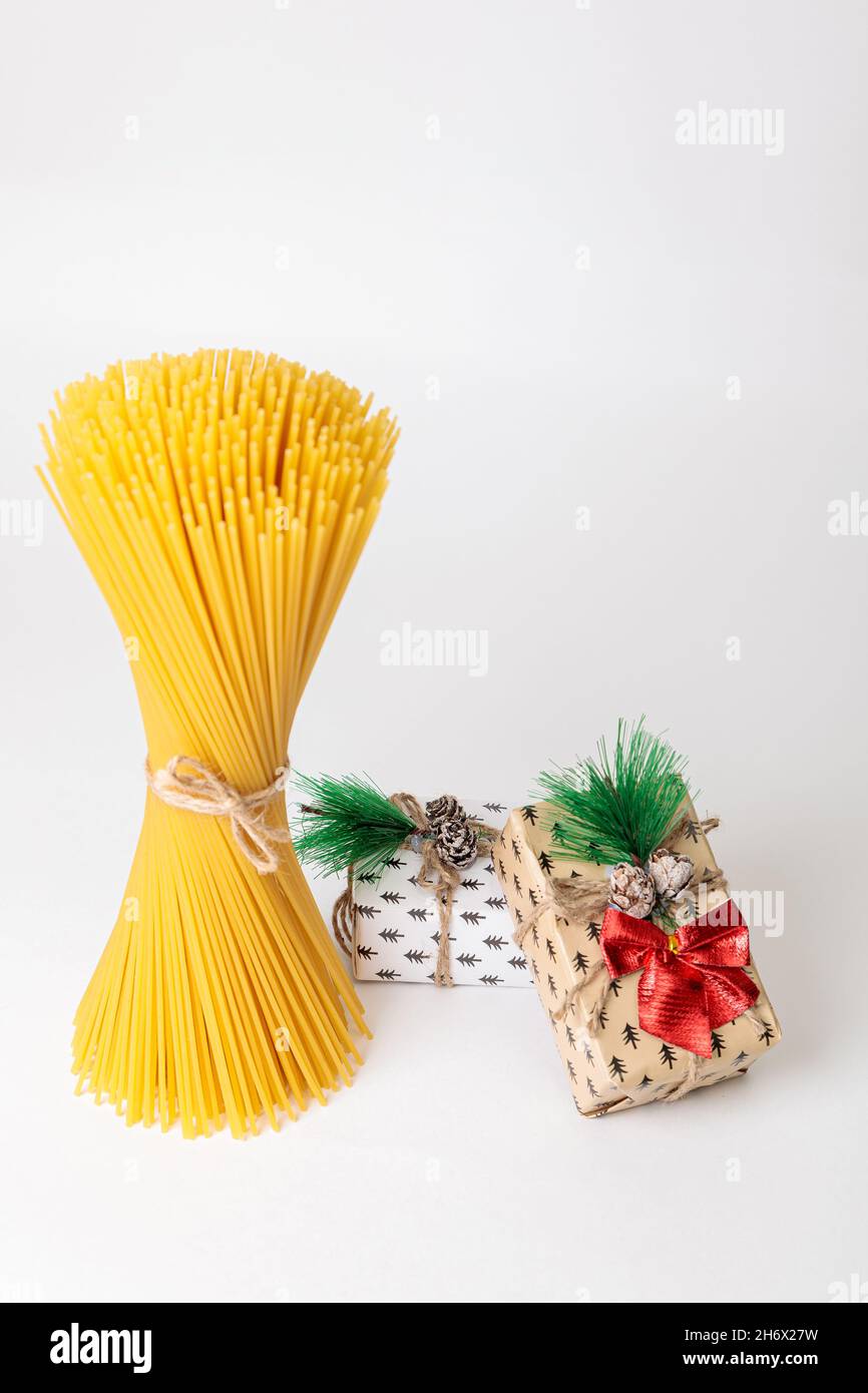 Vertical bunch of raw spaghetti tied with thread, next to boxes for New ...
