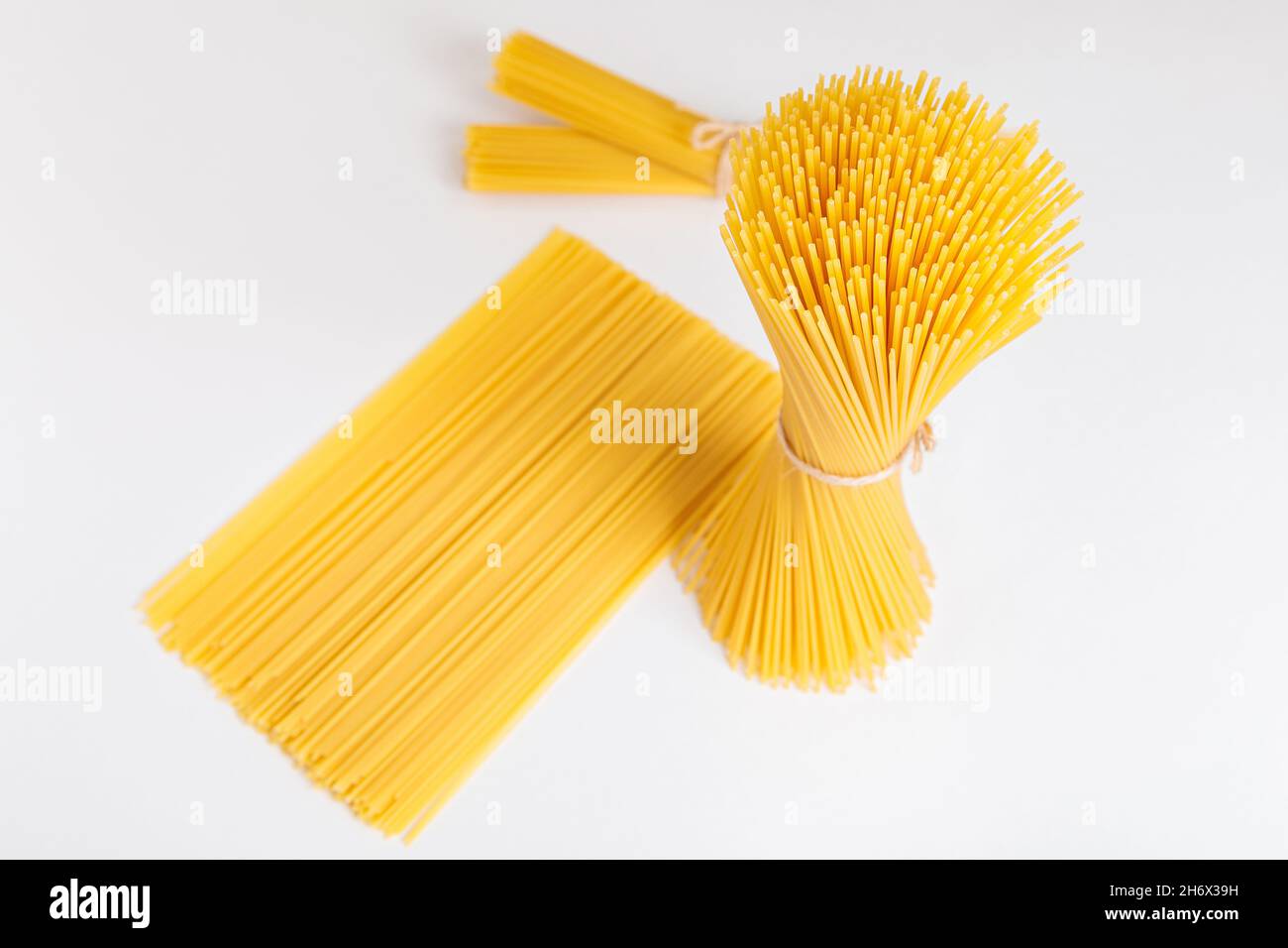 Set of bundles of raw spaghetti, tied with thread, on a white ...