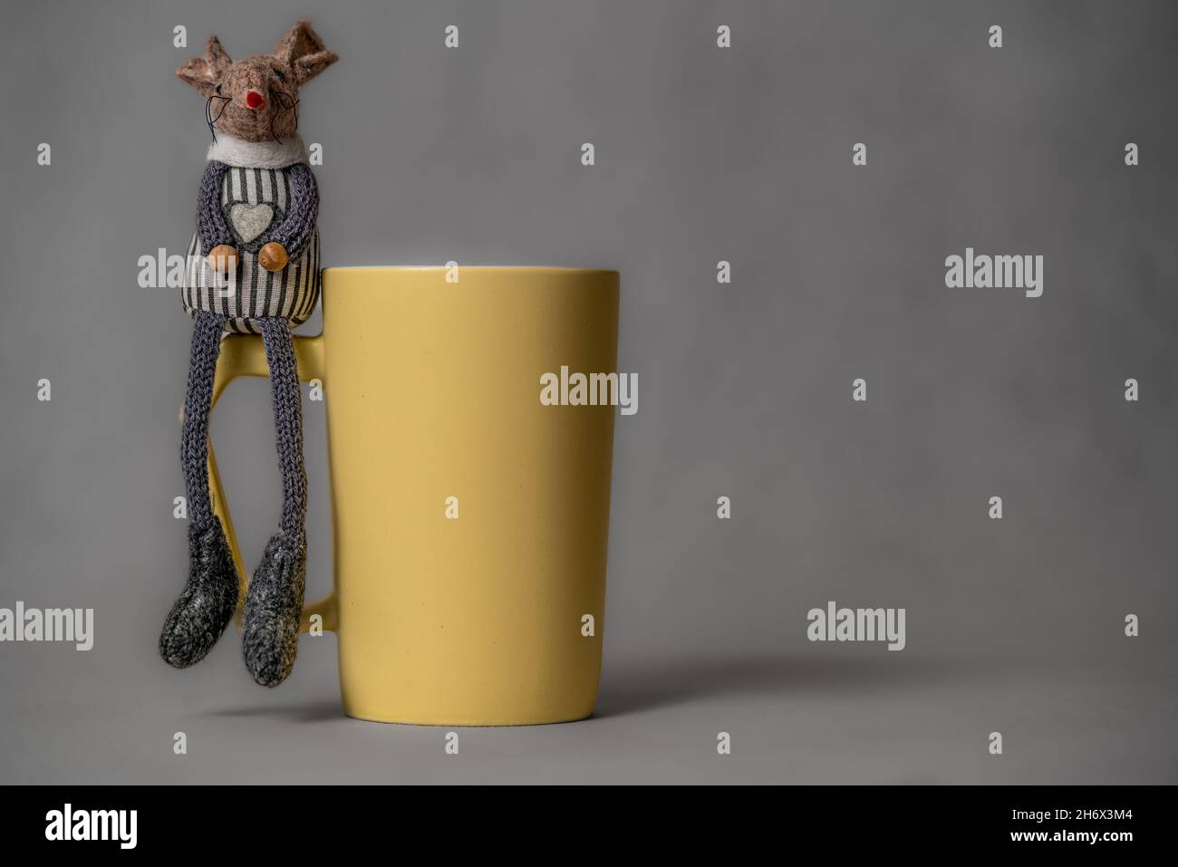 Yellow coffee or tea cup on neutral background and two toy mouses Stock Photo