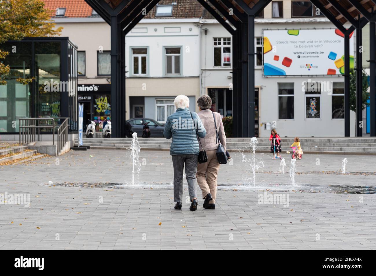 Vilvoorde, Flemish Region - Belgium - 10 17 2021: Two senior woman walking hand in hand at the old market square Stock Photo