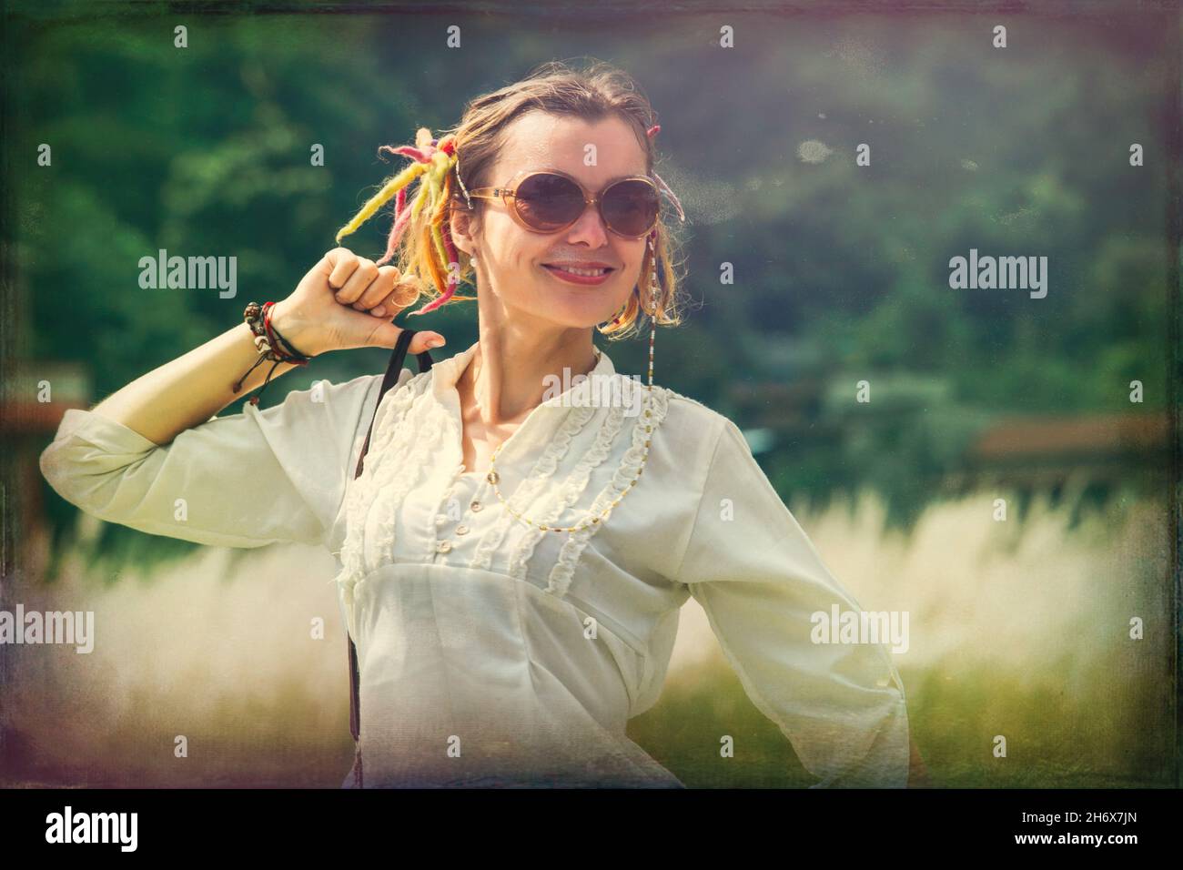 Relaxed young woman in a meadow by the forest in the village Stock Photo