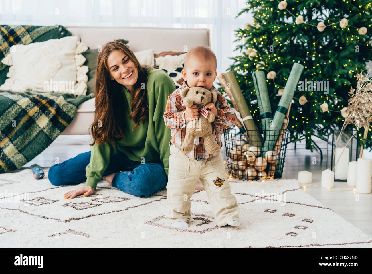 Laughing redhead mom spends time with her little cheerful child in the living room at christmas time Stock Photo