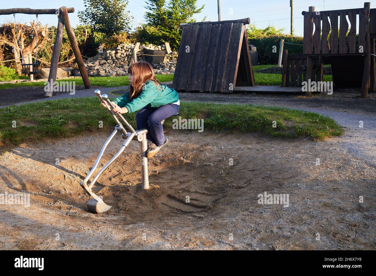 young girl in school uniform playing with a bulldozer in a playground Stock Photo