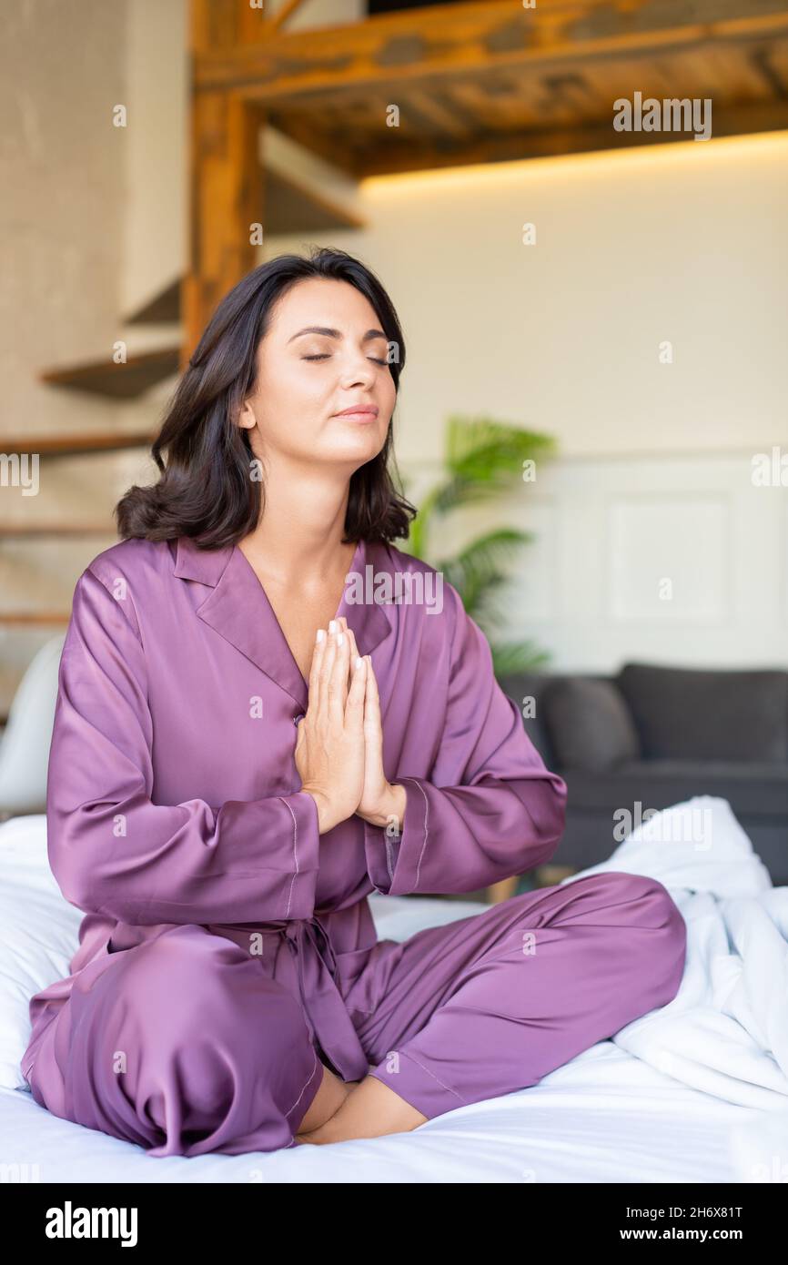 Mettal health and digital detox concept - 40 years old woman meditating on bed. Stock Photo