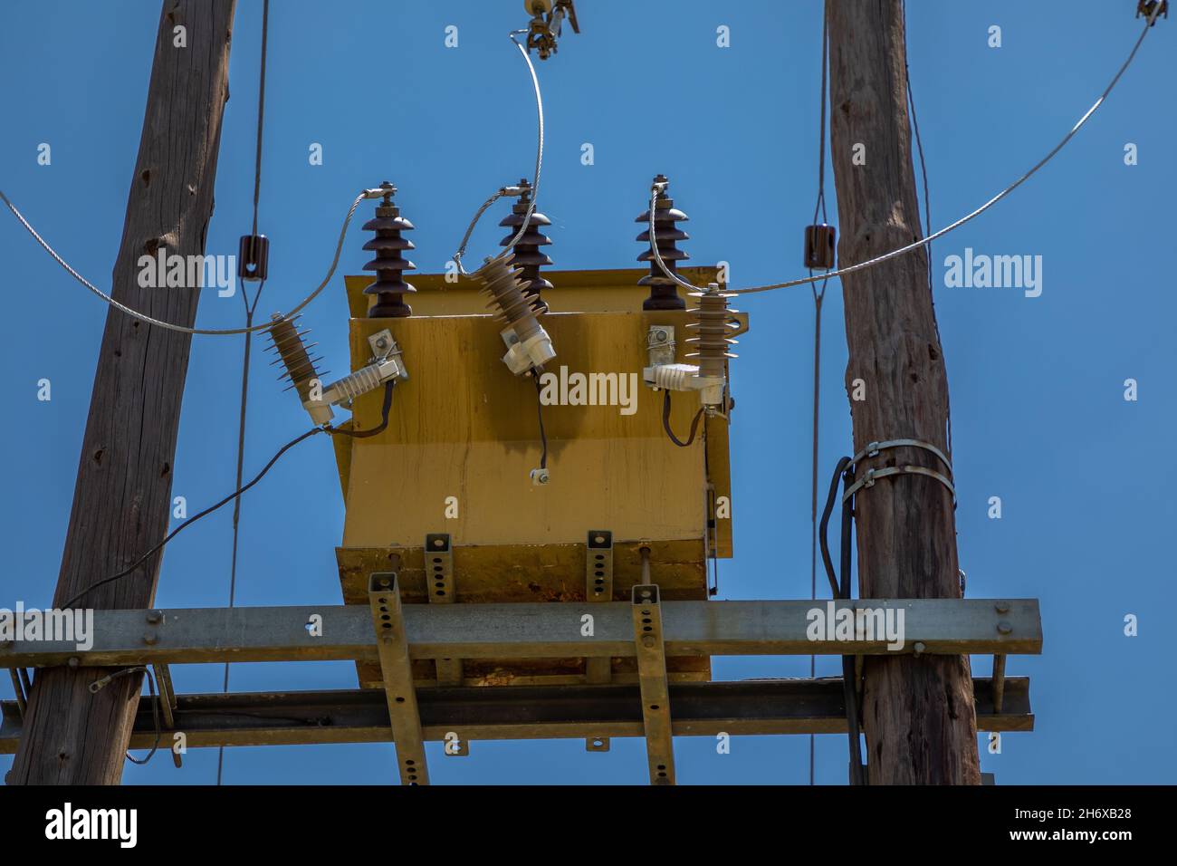 Close up on an old electrical transformer, against the blue sky, build on wooden poles Stock Photo