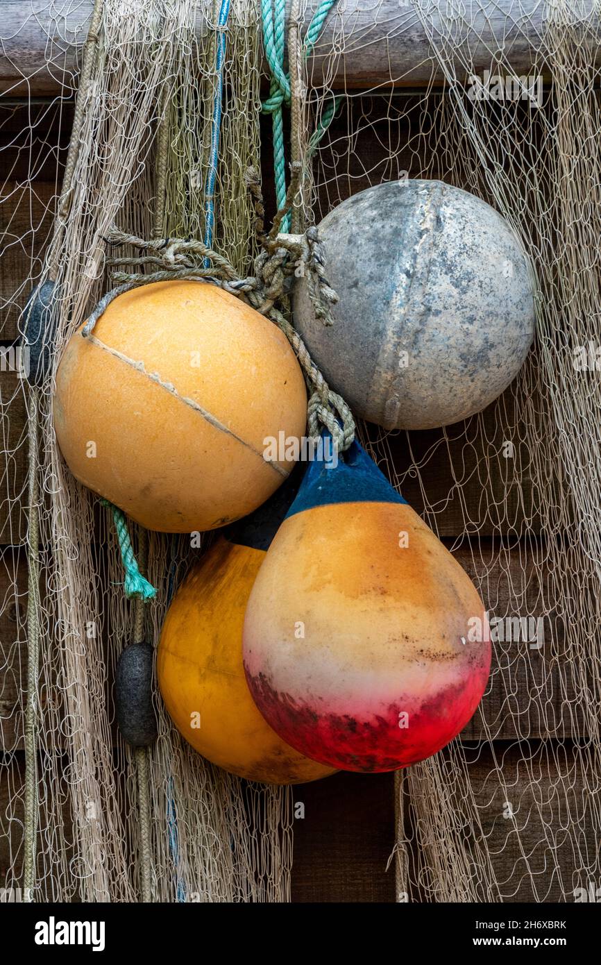 old colourful fishing floats and plastic buoys hanging from the wooden wall of a fishermans shed