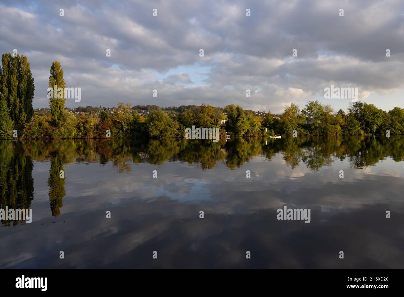 View over the Ruhr-river on the district of Essen Kupferdreh in Germany. The landscape is reflecting in the water. Typical autumn panorama. Stock Photo