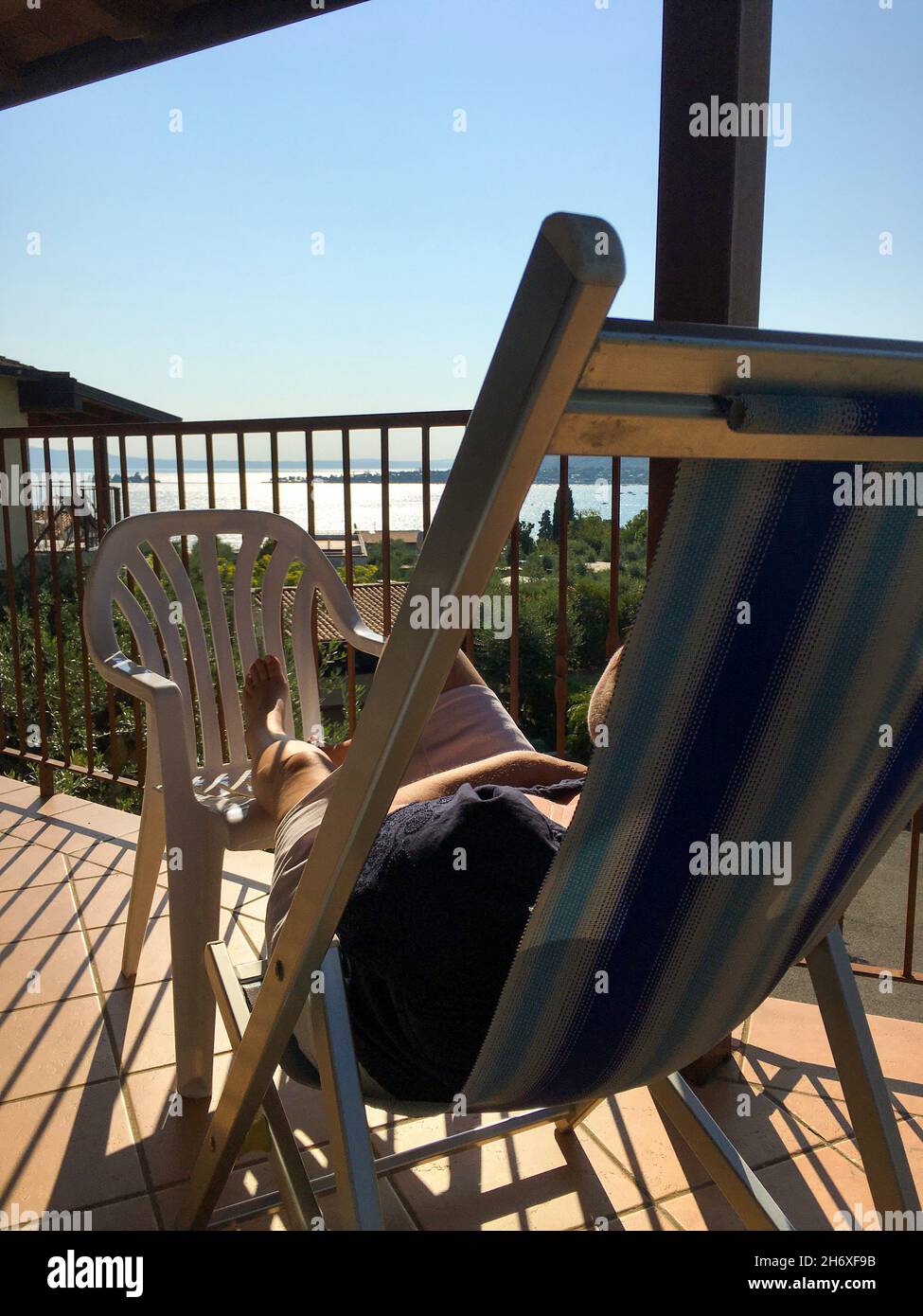 Frau entspannt auf einem Liegestuhl mit Blick auf den Gardasee Stock Photo