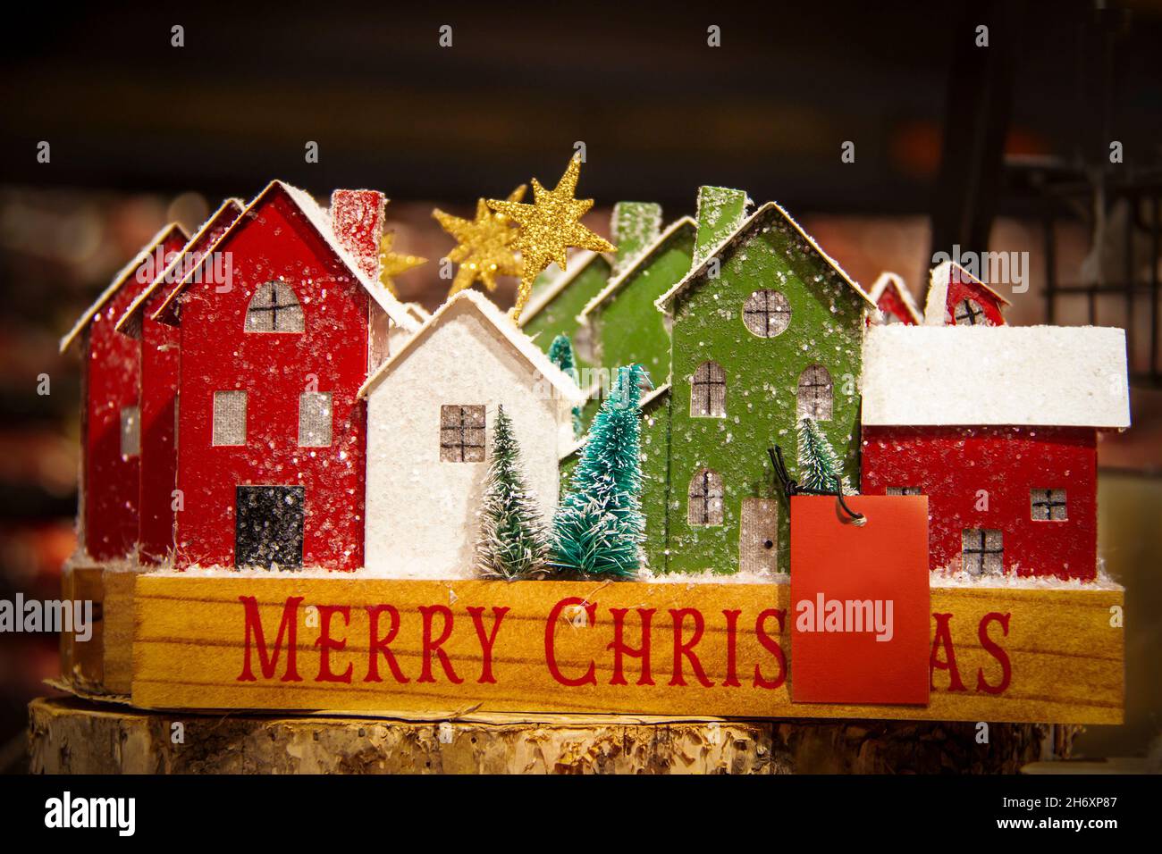 Wooden Christmas village - glittery decor red and green and white houses in Merry Christmas box against blurred background with blank card for message Stock Photo