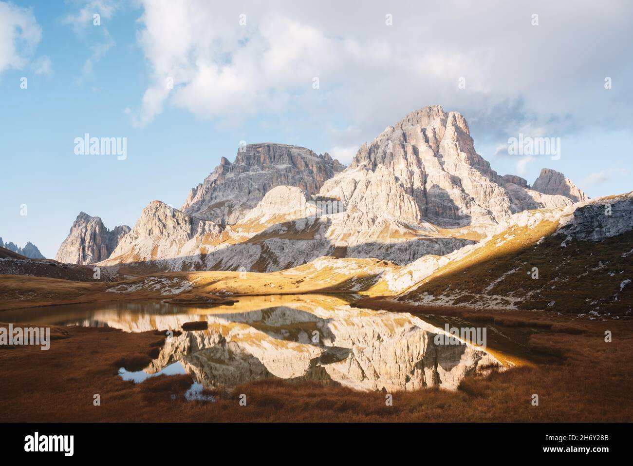 Clear water of alpine lake Piani in the Tre Cime Di Laveredo National Park, Dolomites, Italy. Picturesque landscape with Schusterplatte mountains, orange grass and small lake in autumn Dolomite Alps Stock Photo