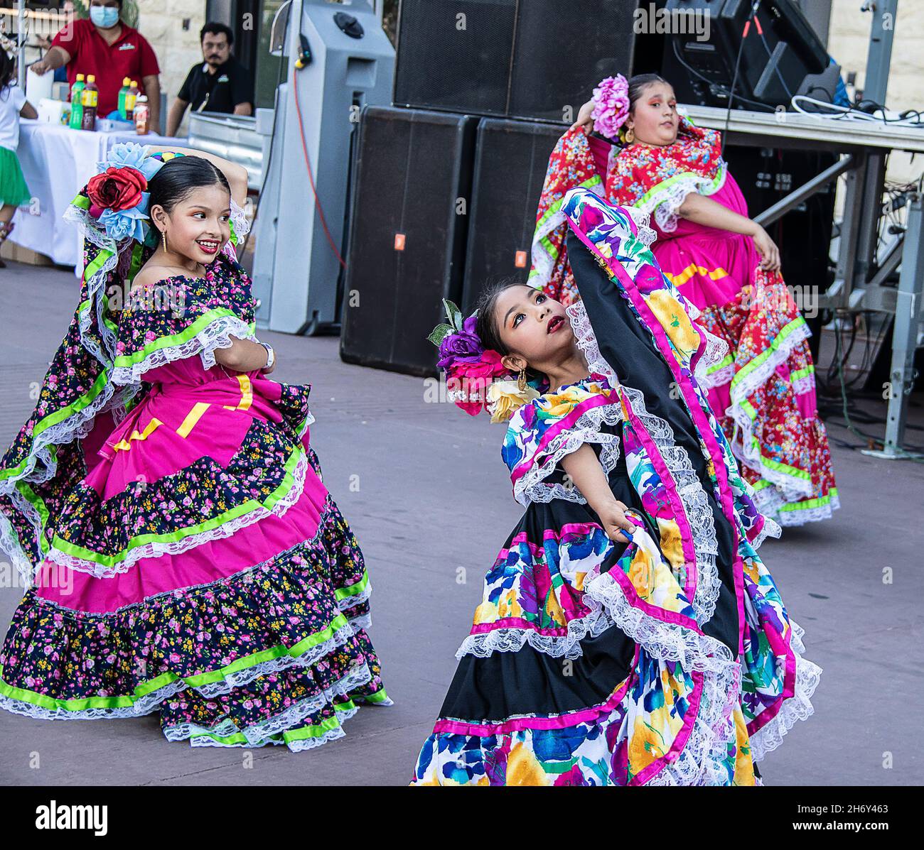 2021 19 09 Tulsa USA - Beautiful young Hispanic girls dance at street festival in beautiful colorful dresses with flowers in their hair in font of sta Stock Photo