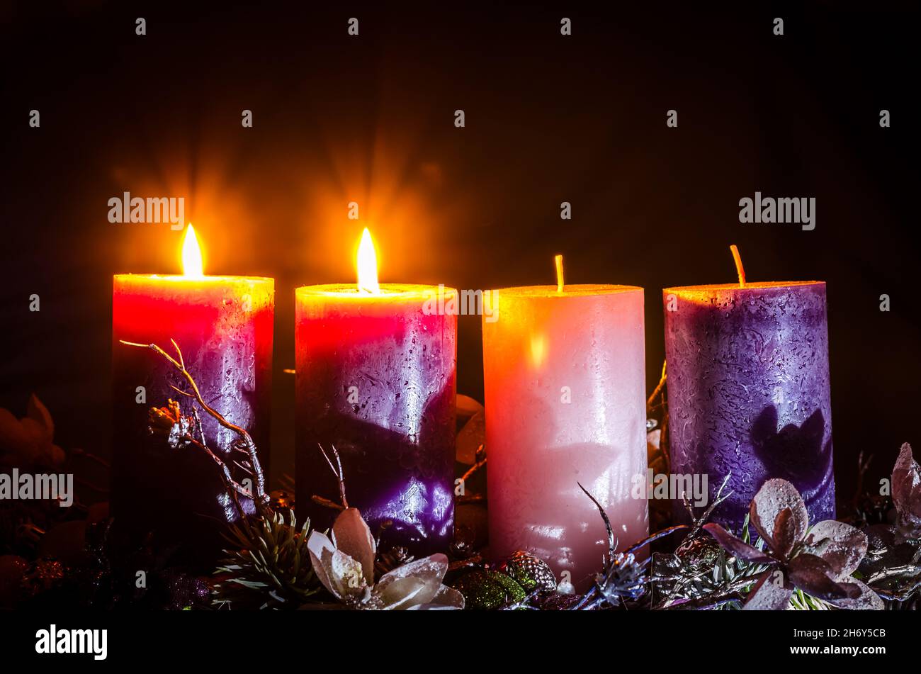 pink and purple candles in advent wreath decoration on black background