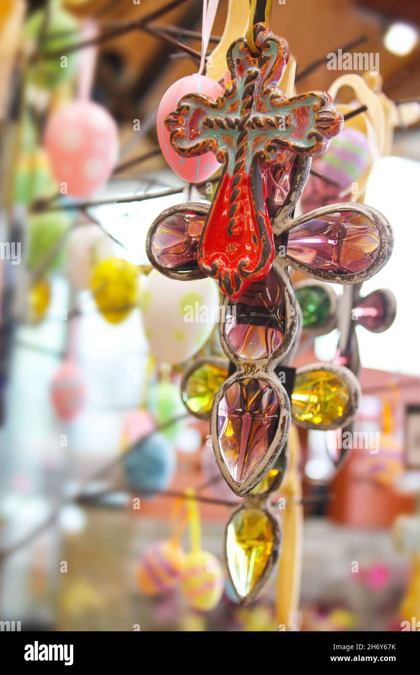 Ceramic cross symbols and Easter Eggs hanging from branches with blurred bokeh background Stock Photo