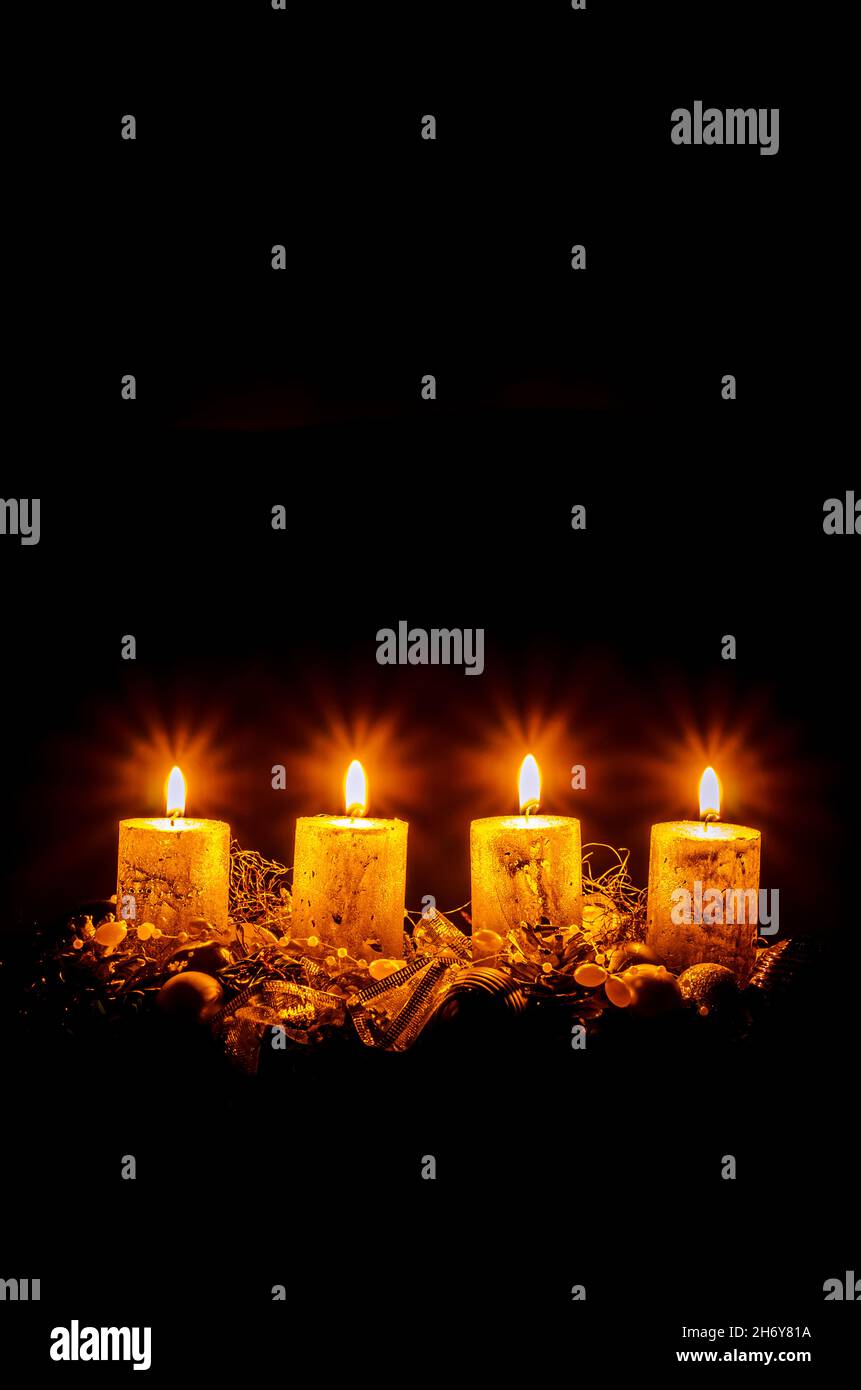 four burning advent candles with decoration and adornments on black background copy space Stock