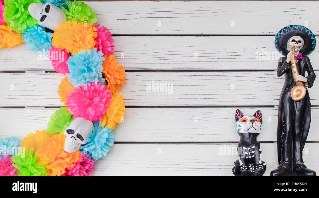 Day of the Dead background - White painted plank background with colorful skull wreath on one side and Mexican skeleton mariachi player and dog with c Stock Photo