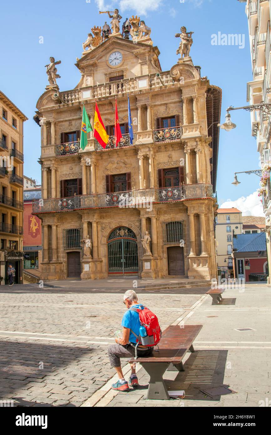 Pilgrim resting in the Plaza Consistorial while walking Camino de Santiago the way of St James pilgrimage route through the city of Pamplona  Spain Stock Photo