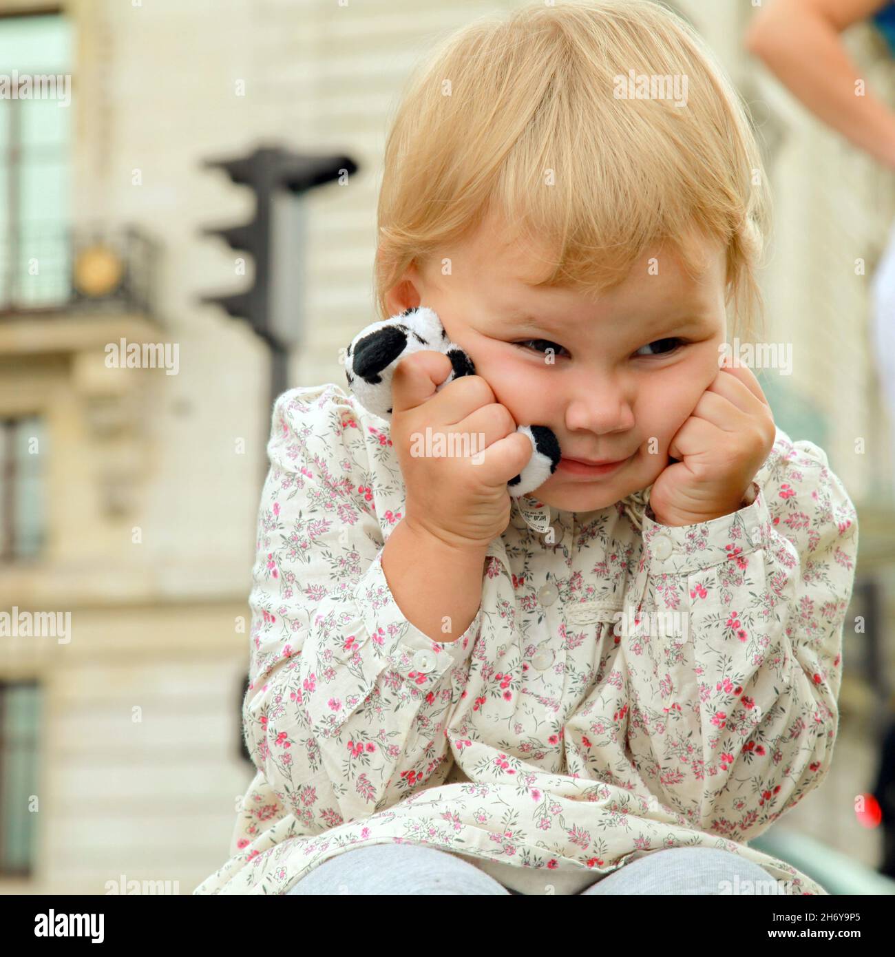 Angry blond baby girl with a toy in hands Stock Photo