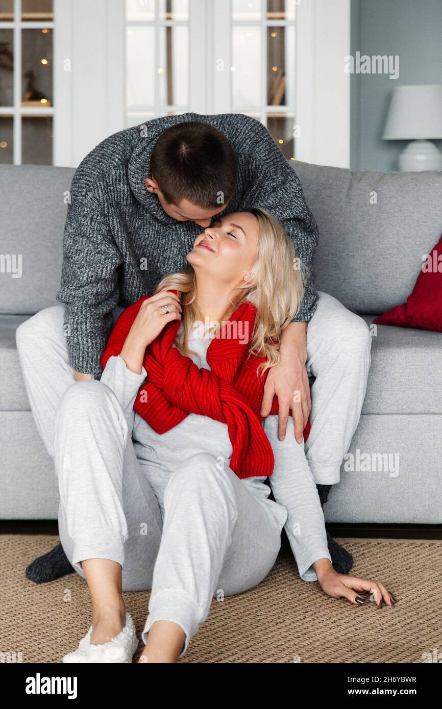 Intimate married couple hug sit on comfortable couch at home on cozy Christmas or New Year