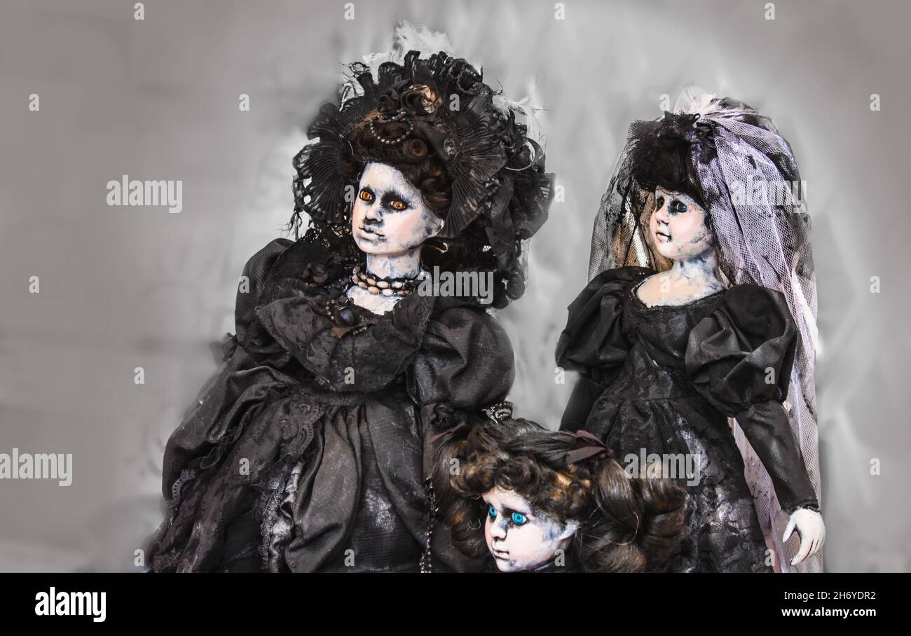 Three spooky gothic dolls dressed in black Victorian dresses - one is a bride - with dead looking skin and strange eyes Stock Photo