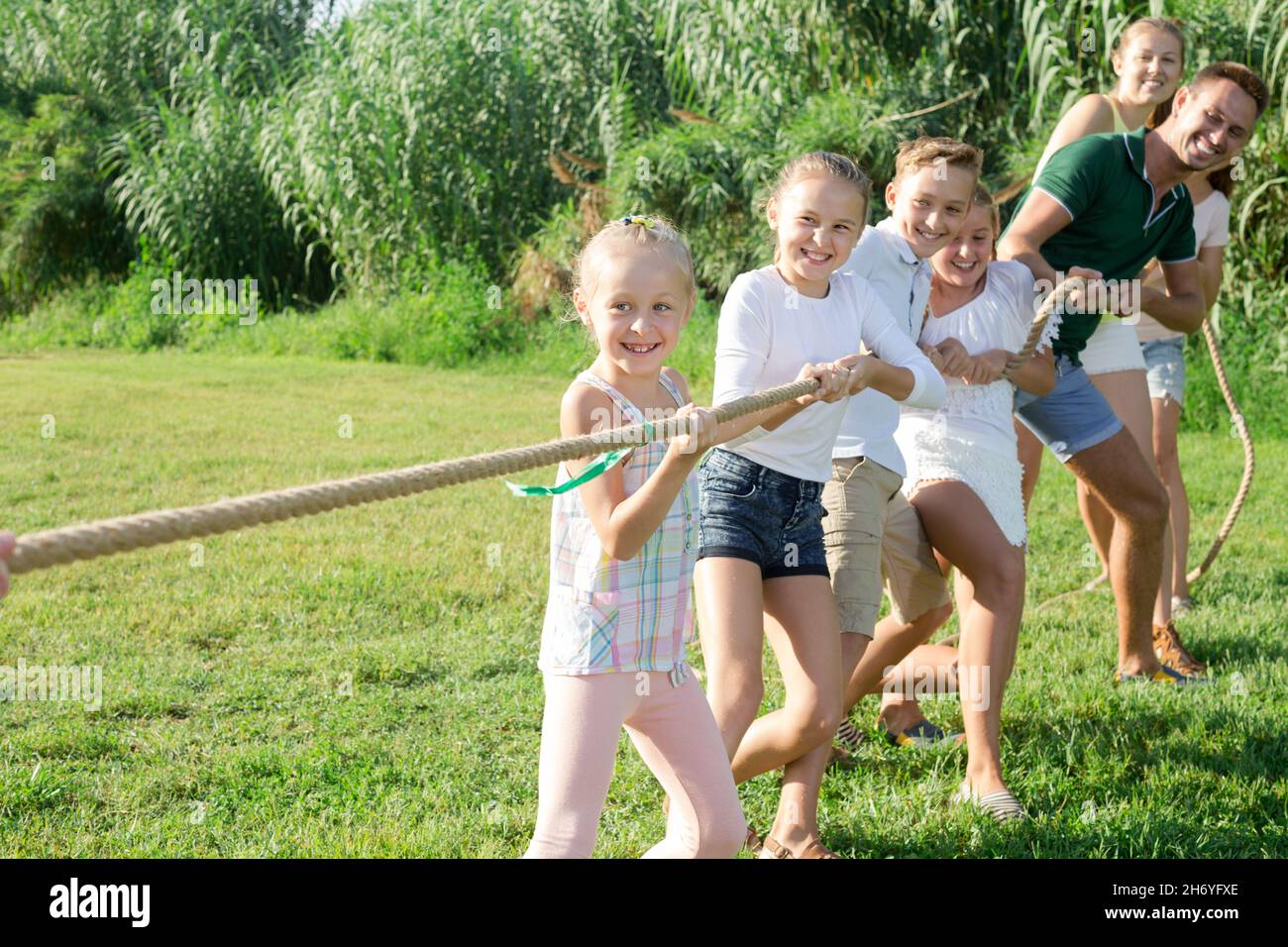 Positive kids with parents playing tug of war Stock Photo